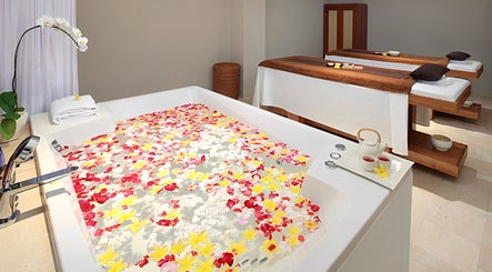 Petal-filled spa bath at Visala Spa The Bandha, Bali, Bali, ID with serene massage tables nearby.