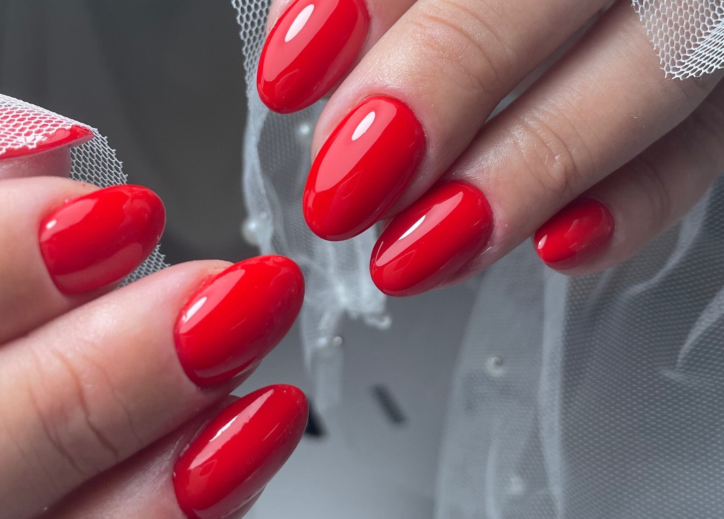 Vibrant red manicured nails at ŻanaNailsStudio, Edinburgh, Scotland, GB showcasing excellent craftsmanship.