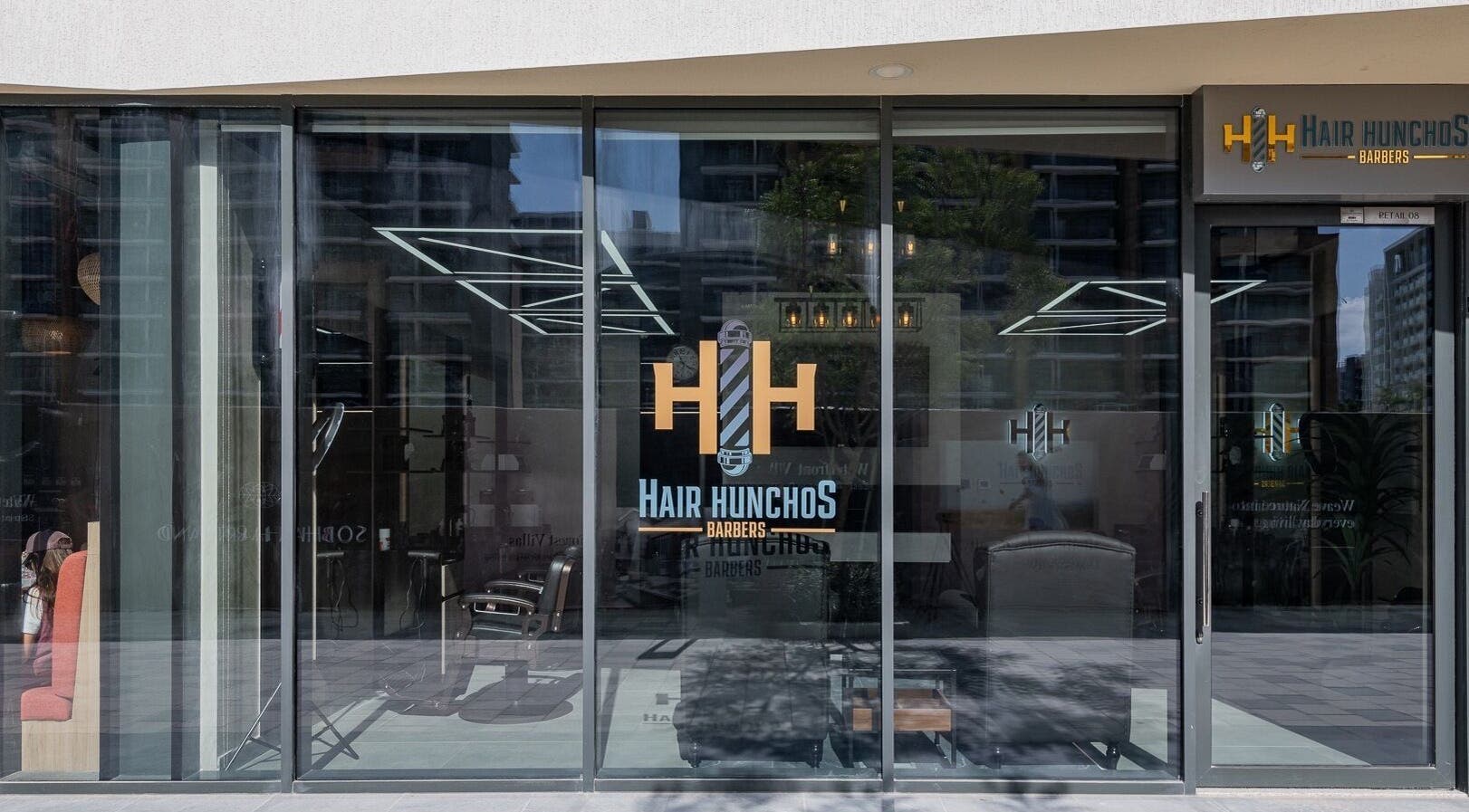 Front view of Hair Hunchos Barbers in Dubai, Dubai, AE, showcasing modern glass facade.