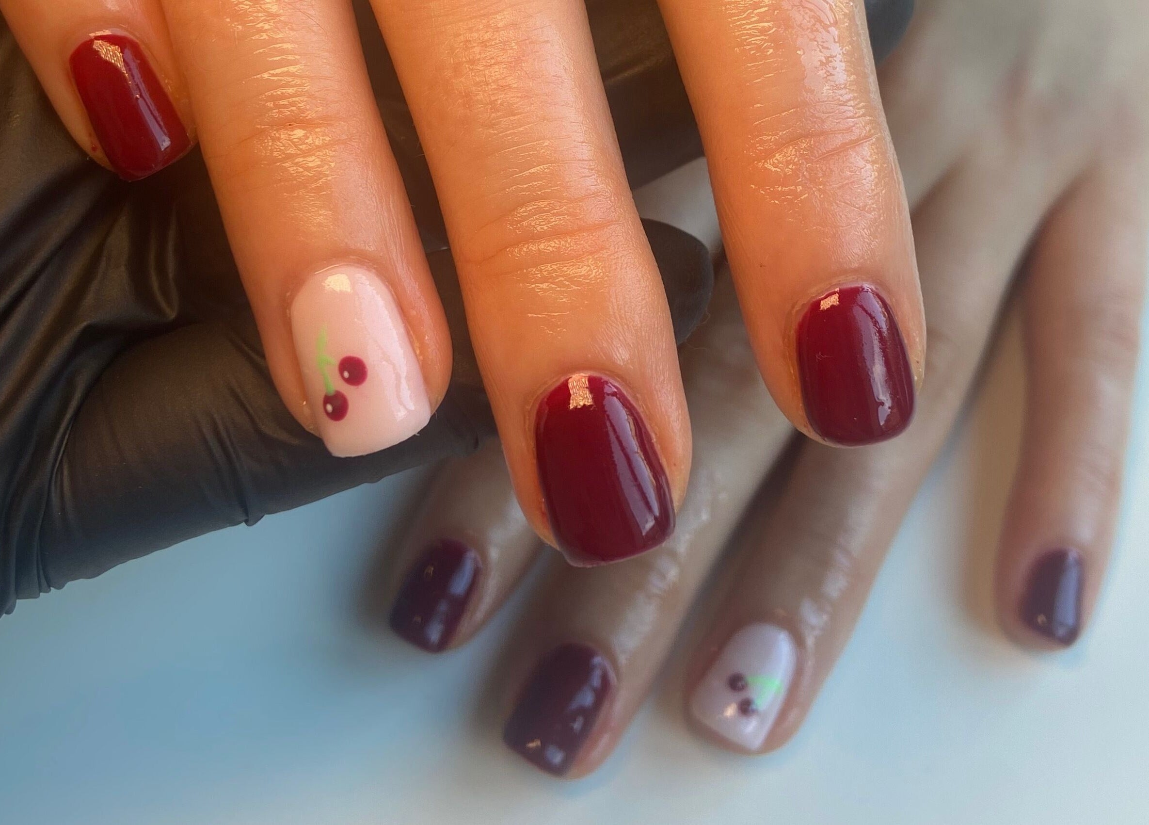 Elegant cherry nail art at Glos Nails by April in Shirley, England, GB. Perfect manicure with glossy finish.