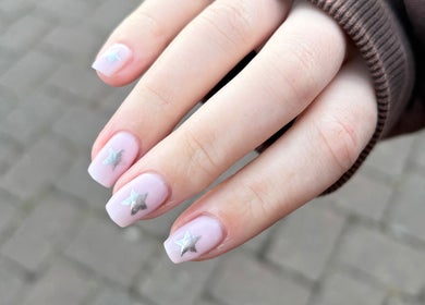 Close-up of a hand showing pink nails with silver stars at Glos Nails by April, Shirley, England, GB.