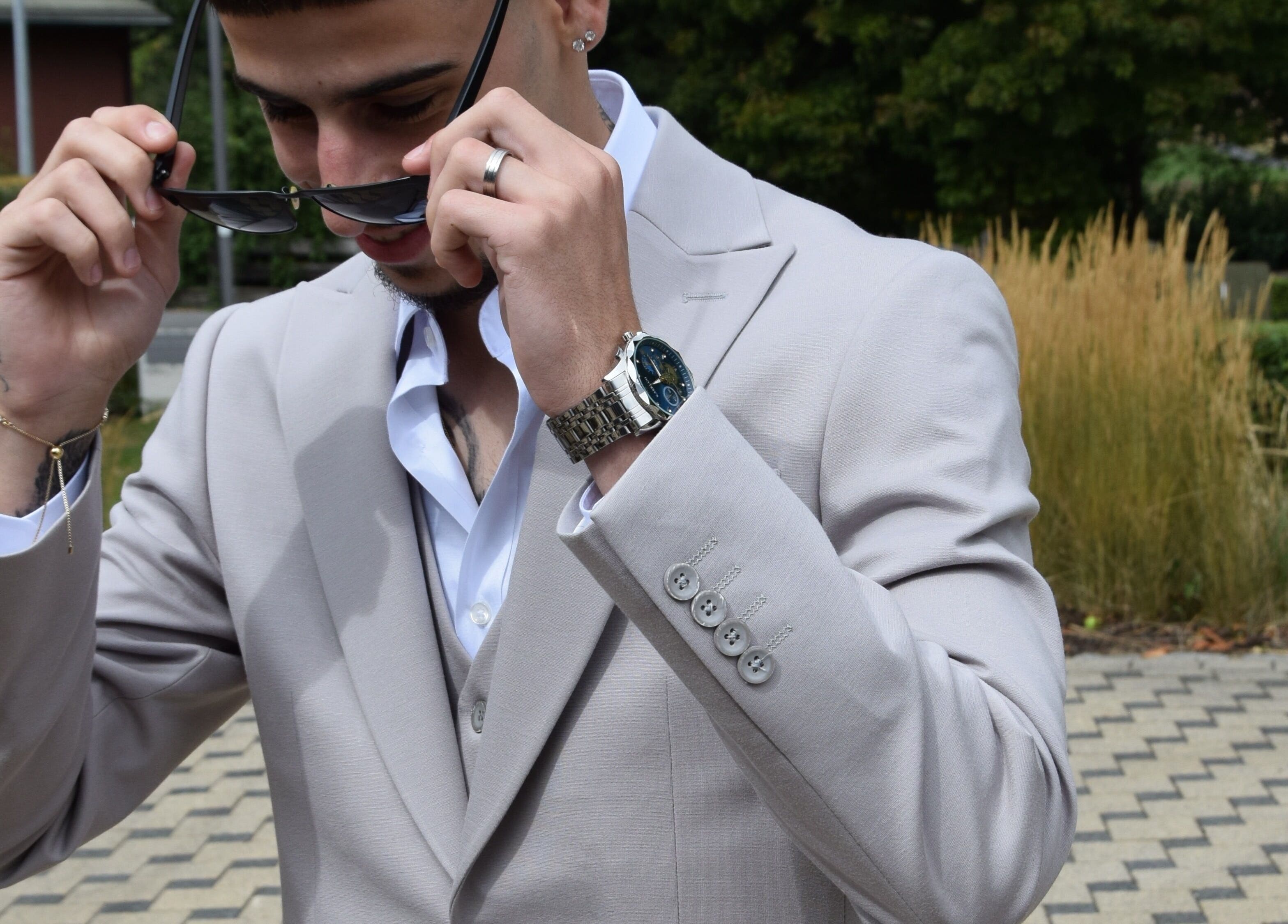 Man in a stylish suit adjusting sunglasses at IzzyCuts, Klierf, Kanton Klierf, LU.
