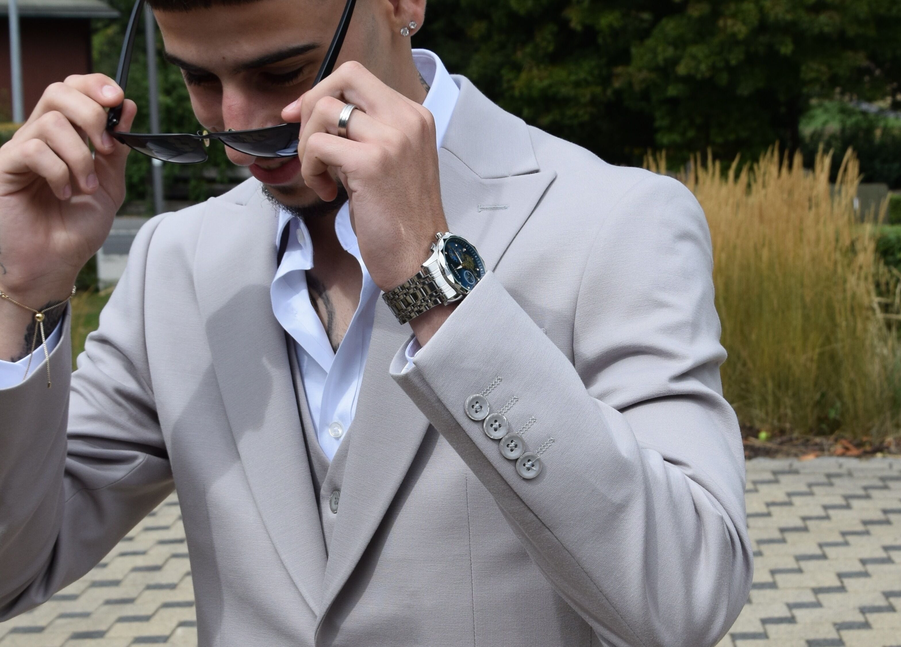 Man in a stylish suit adjusting sunglasses at IzzyCuts, Klierf, Kanton Klierf, LU.