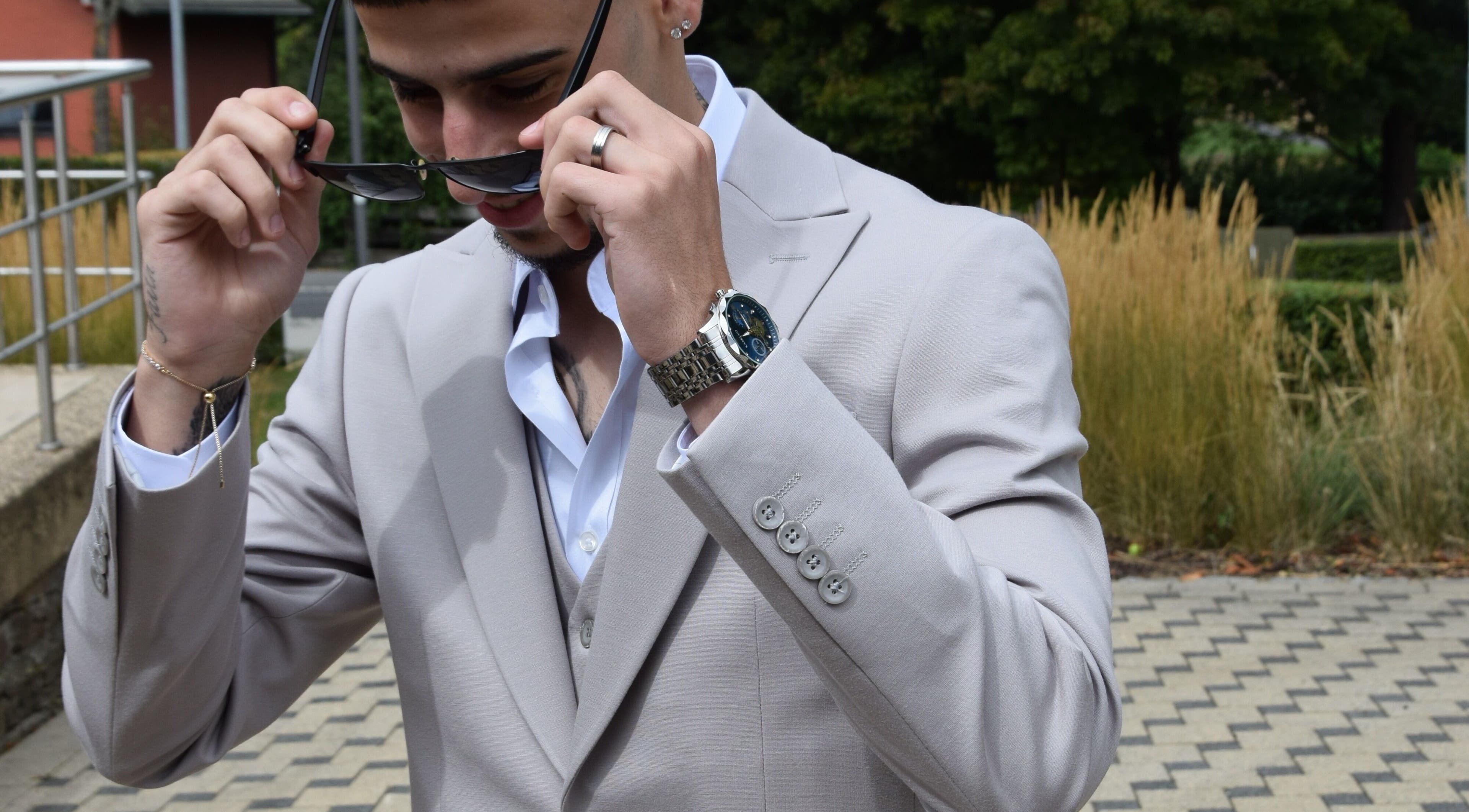 Man in a stylish suit adjusting sunglasses at IzzyCuts, Klierf, Kanton Klierf, LU.