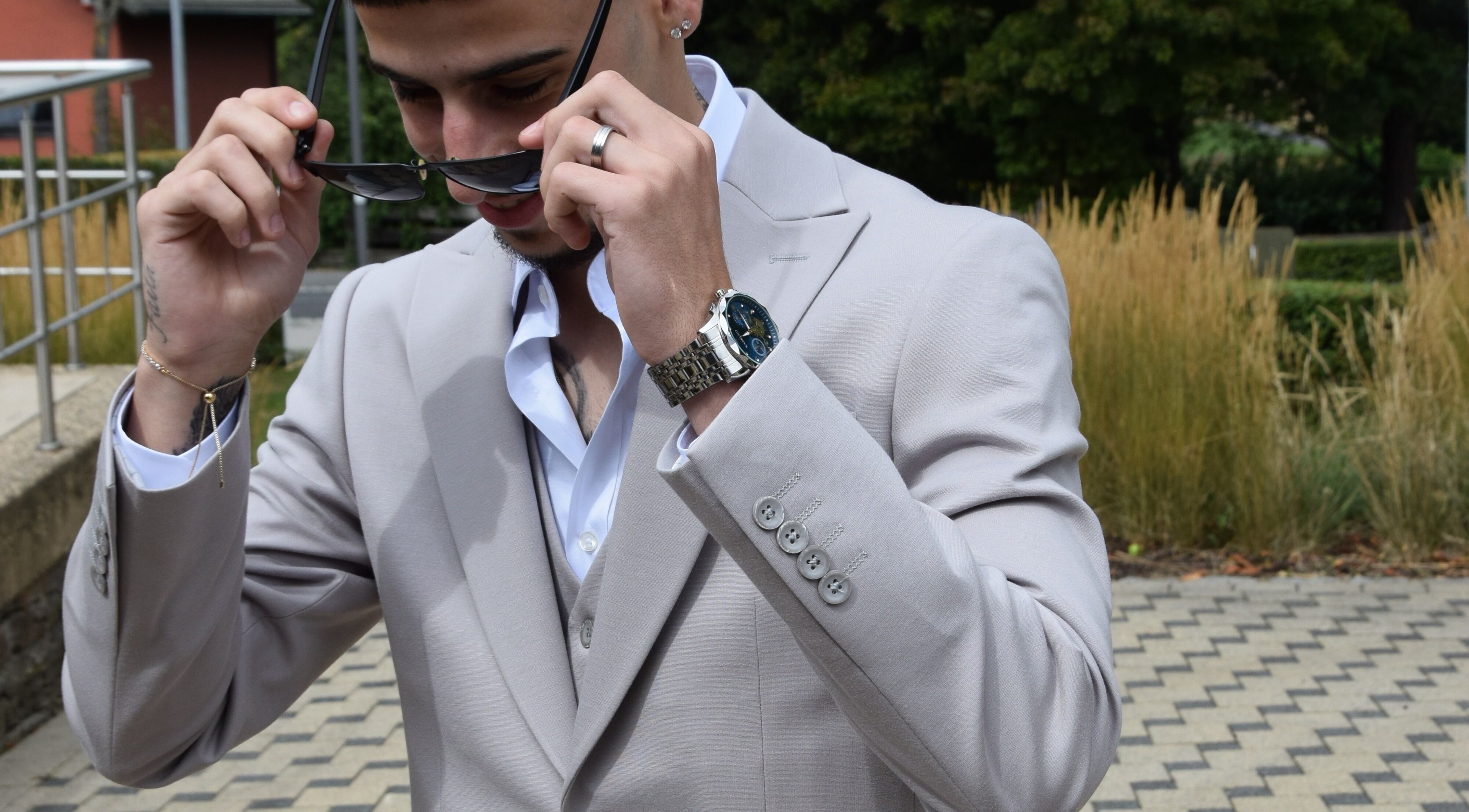 Man in a stylish suit adjusting sunglasses at IzzyCuts, Klierf, Kanton Klierf, LU.