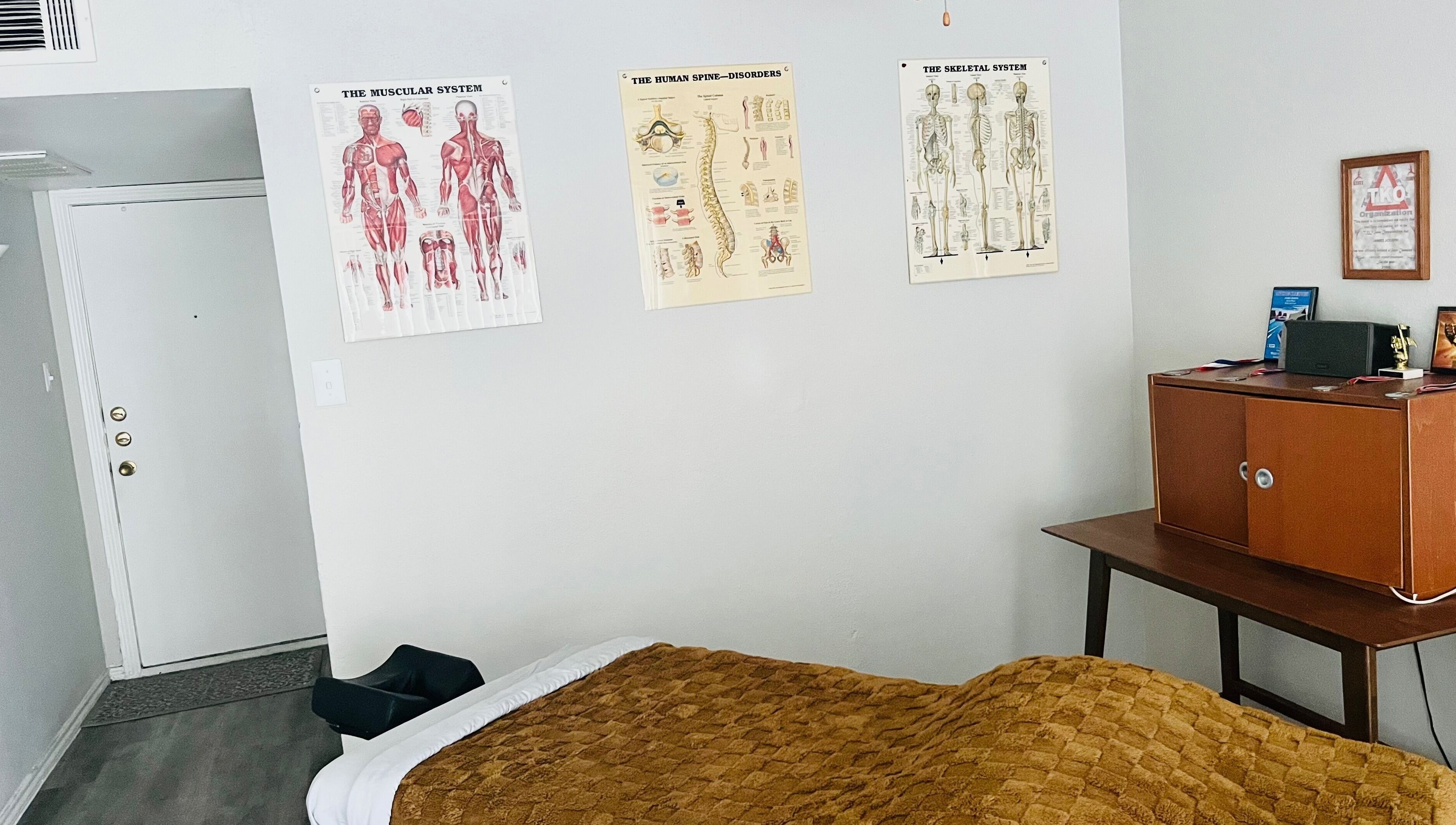 Tranquil massage room at James Joseph L.M.T in Houston, Texas, US with anatomical charts and warm decor.