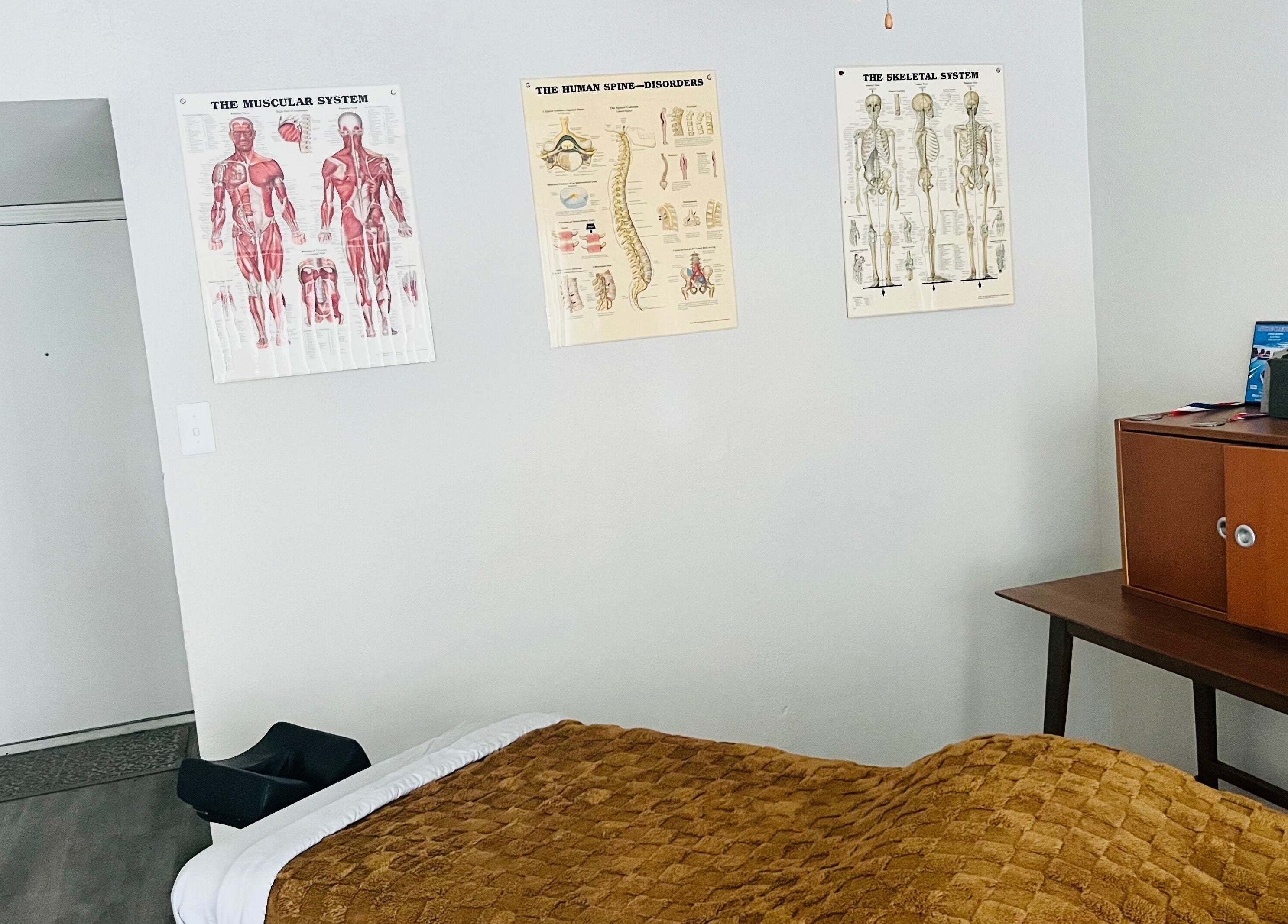 Tranquil massage room at James Joseph L.M.T in Houston, Texas, US with anatomical charts and warm decor.