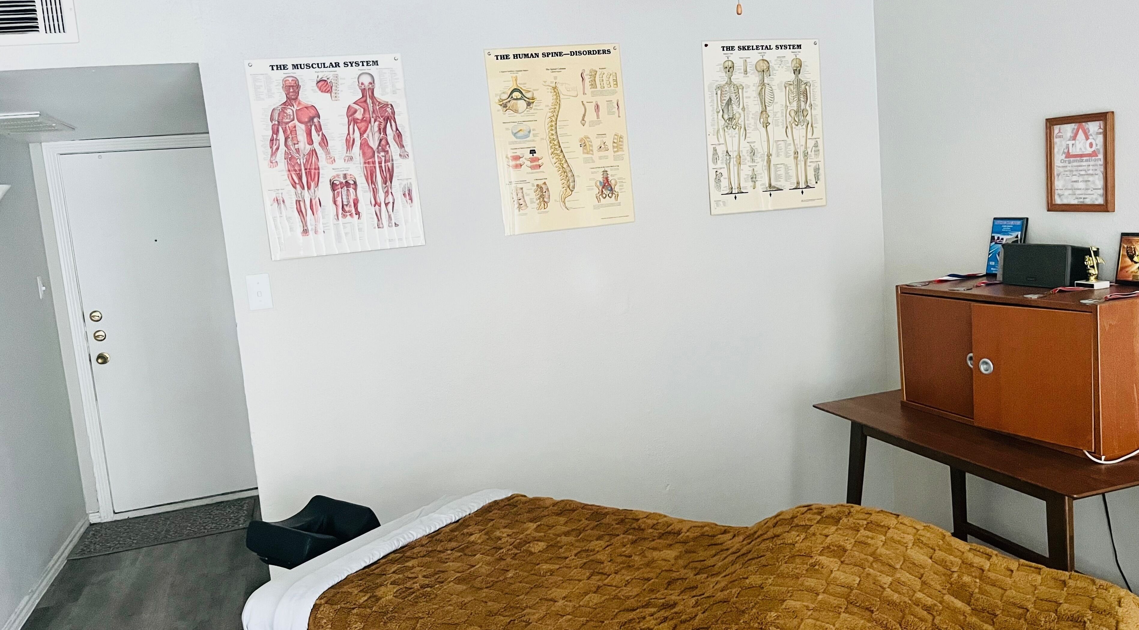 Tranquil massage room at James Joseph L.M.T in Houston, Texas, US with anatomical charts and warm decor.