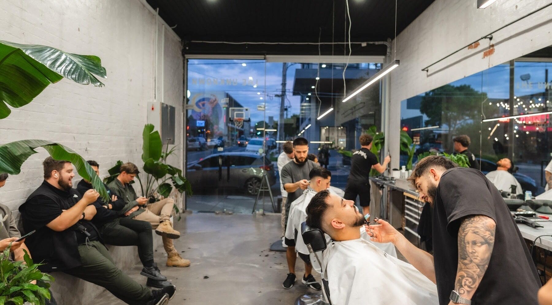 Modern interior of The Unknown Barbers - Preston in Melbourne, Victoria, AU with clients receiving haircuts.