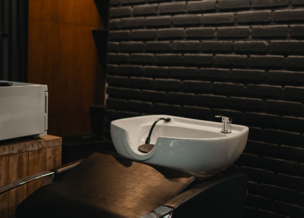 Luxurious hair wash station at Stevie's in Bali, Bali, ID, set against a sleek black brick wall.
