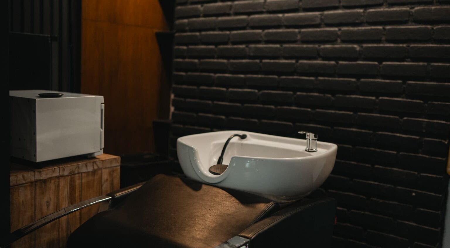 Modern hair wash station at Stevie's in Bali, Bali, ID with sleek design and black brick backdrop.