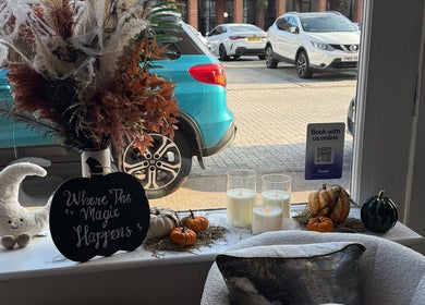 Cozy autumn-themed window display at The Coven Hair Lounge in Aylesbury, England, GB with pumpkins and candles.