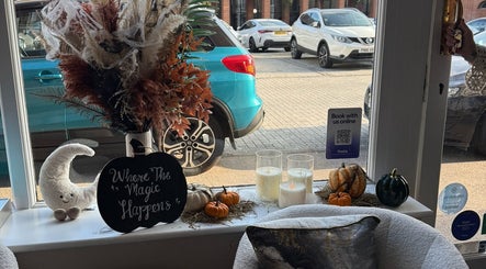 Cozy autumn-themed window display at The Coven Hair Lounge in Aylesbury, England, GB with pumpkins and candles.
