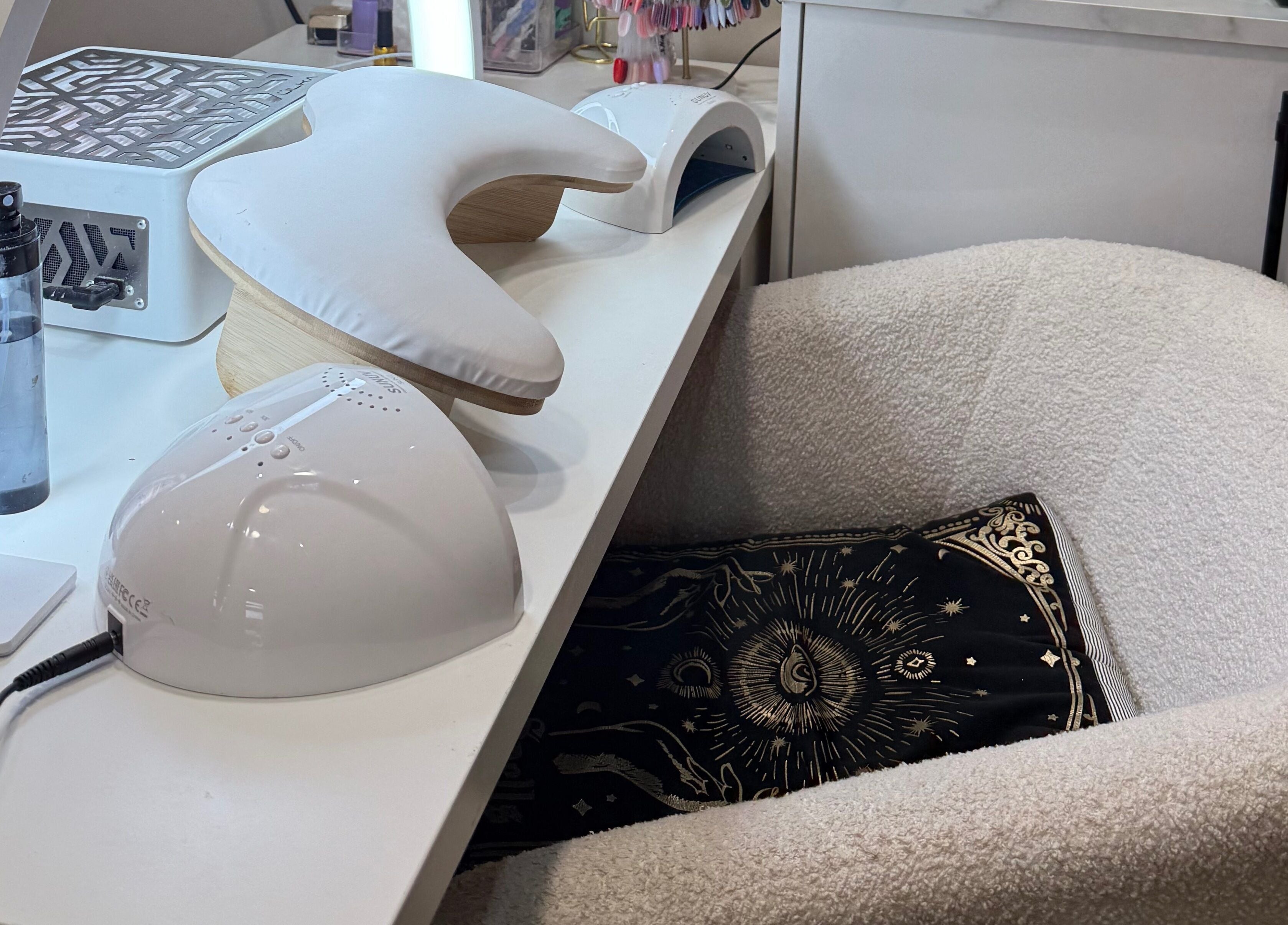 Modern nail station at The Coven Beauty Lounge in Aylesbury, England, GB with plush chair and sun motif pillow.