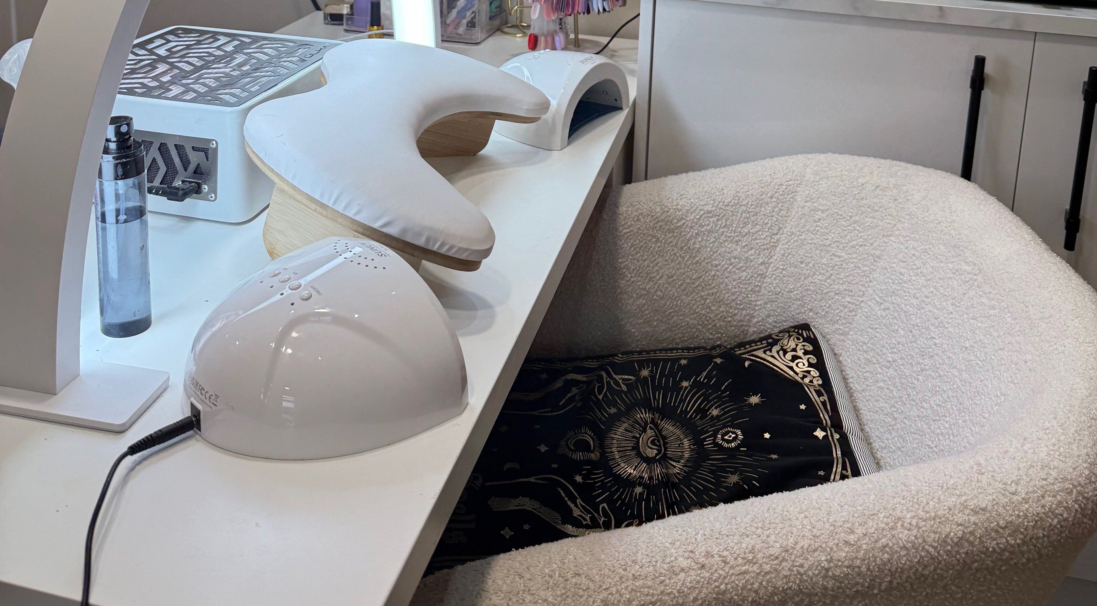 Modern nail station at The Coven Beauty Lounge in Aylesbury, England, GB with plush chair and sun motif pillow.