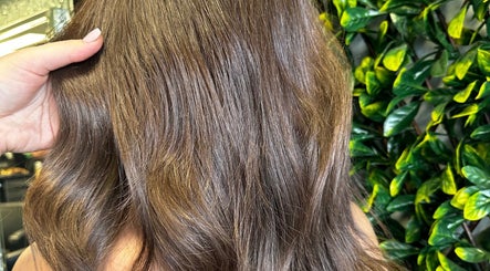 Shiny brown hair styled at SBKHair&Beauty, Crestmead, Queensland, AU with a lush green backdrop.