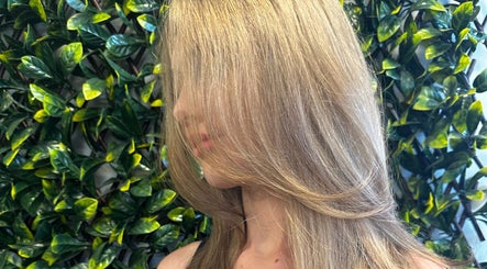 Blonde hair styled with volume at SBKHair&Beauty, Crestmead, Queensland, AU, against a leafy background.