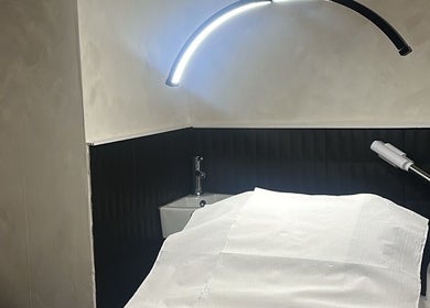 Calm treatment room at Made By Mel in Livingston, Scotland, GB with modern lighting and white linens.