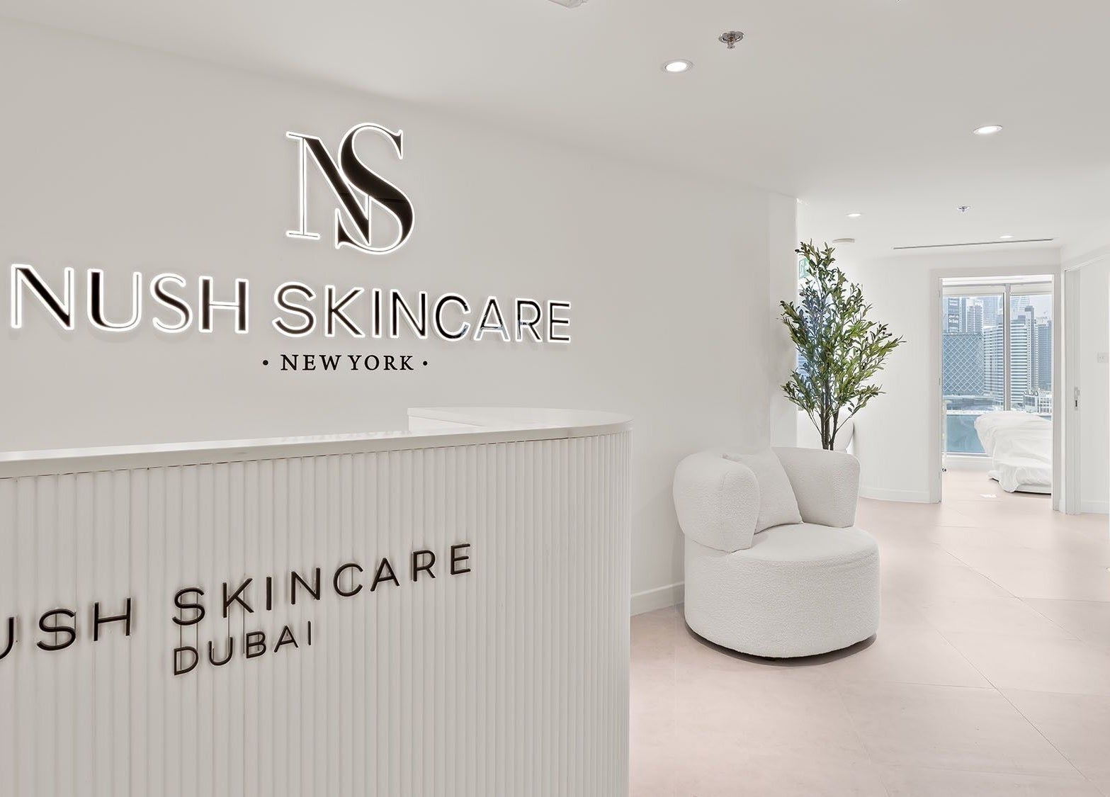 Reception area of Nush Skincare Dubai, Dubai, AE, featuring sleek modern decor and a cozy lounge chair.