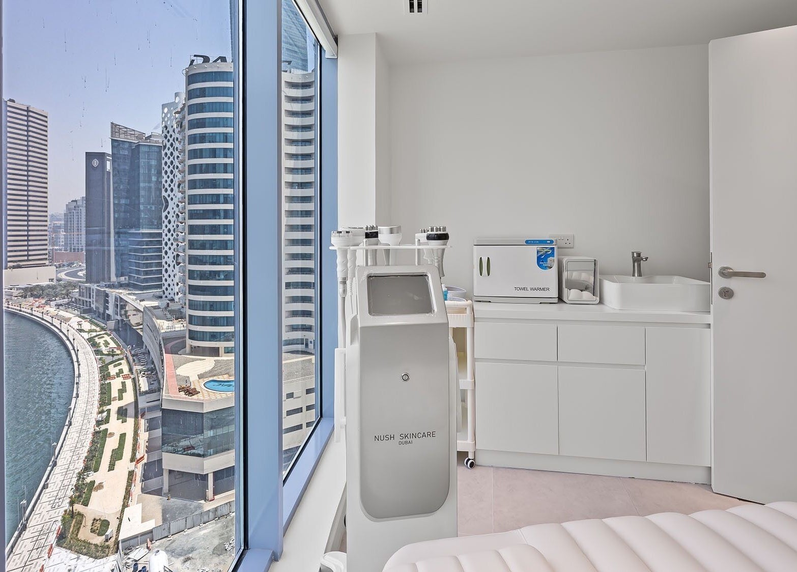 Spacious skincare room at Nush Skincare Dubai, Dubai, AE, overlooking city skyline and canal.