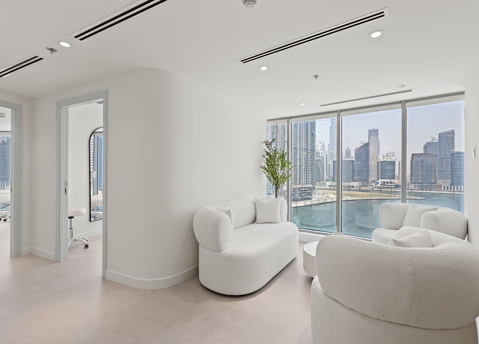 Elegant lounge with city skyline view at Nush Skincare Dubai, Dubai, Dubai, AE, featuring plush white seating.