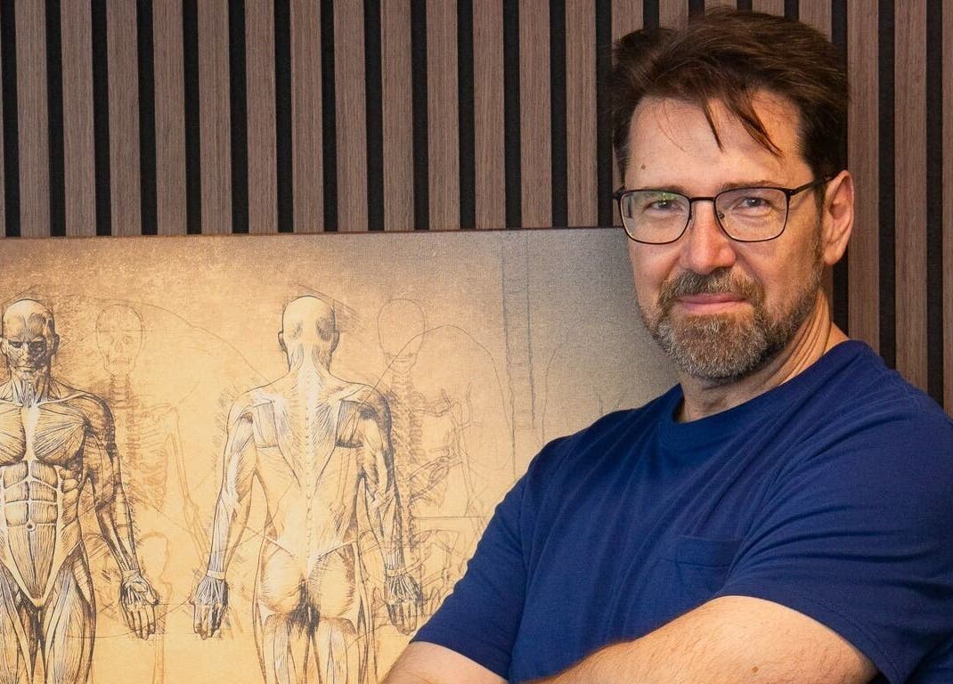 Expert standing at VitaKinesis - movement is life, Los Angeles, California, US, with anatomical artwork.