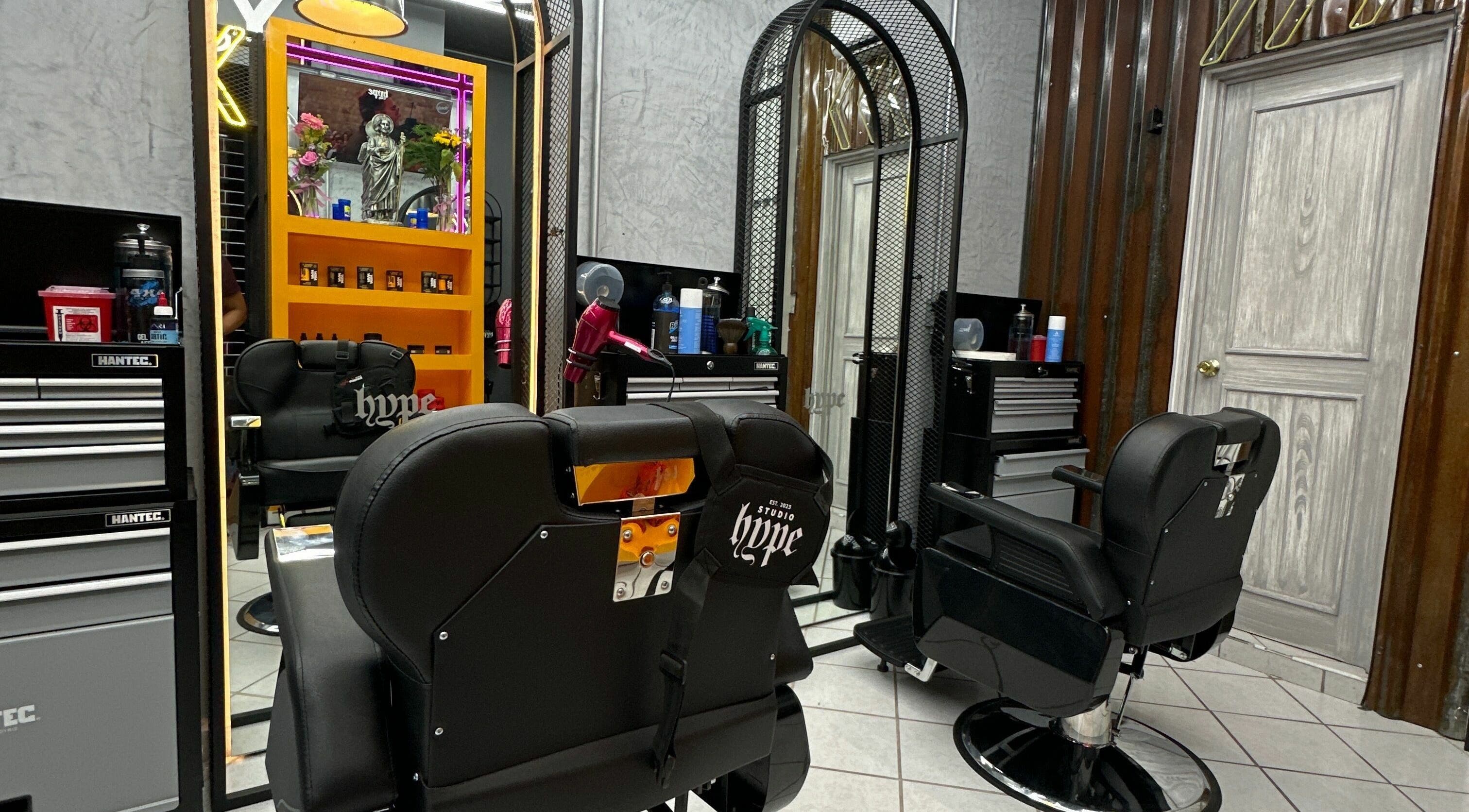 Interior moderno de Studio Hype en Tehuacán, Puebla, MX. Silla de barbero cerca de un espejo iluminado.