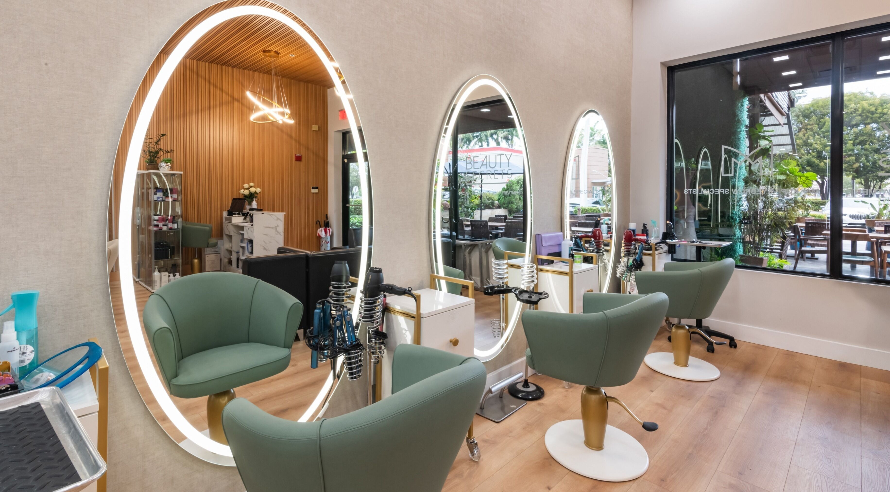 Estaciones de belleza en Beauty Secrets Spa, Doral, Florida, US, con sillones verdes y espejos iluminados.