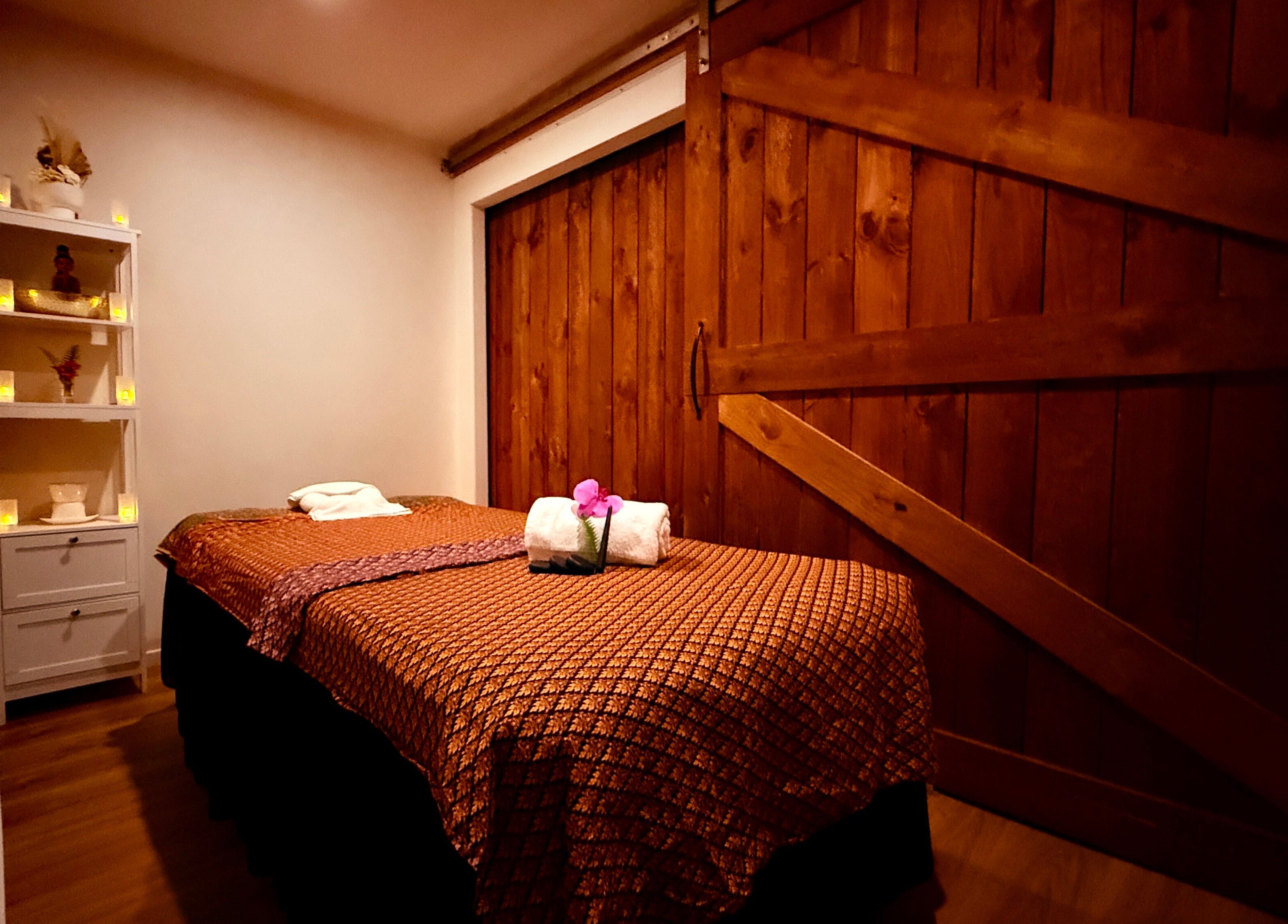 Tranquil massage room at Sanctuary Glenfield, Auckland, NZ, featuring wood accents and mood lighting.