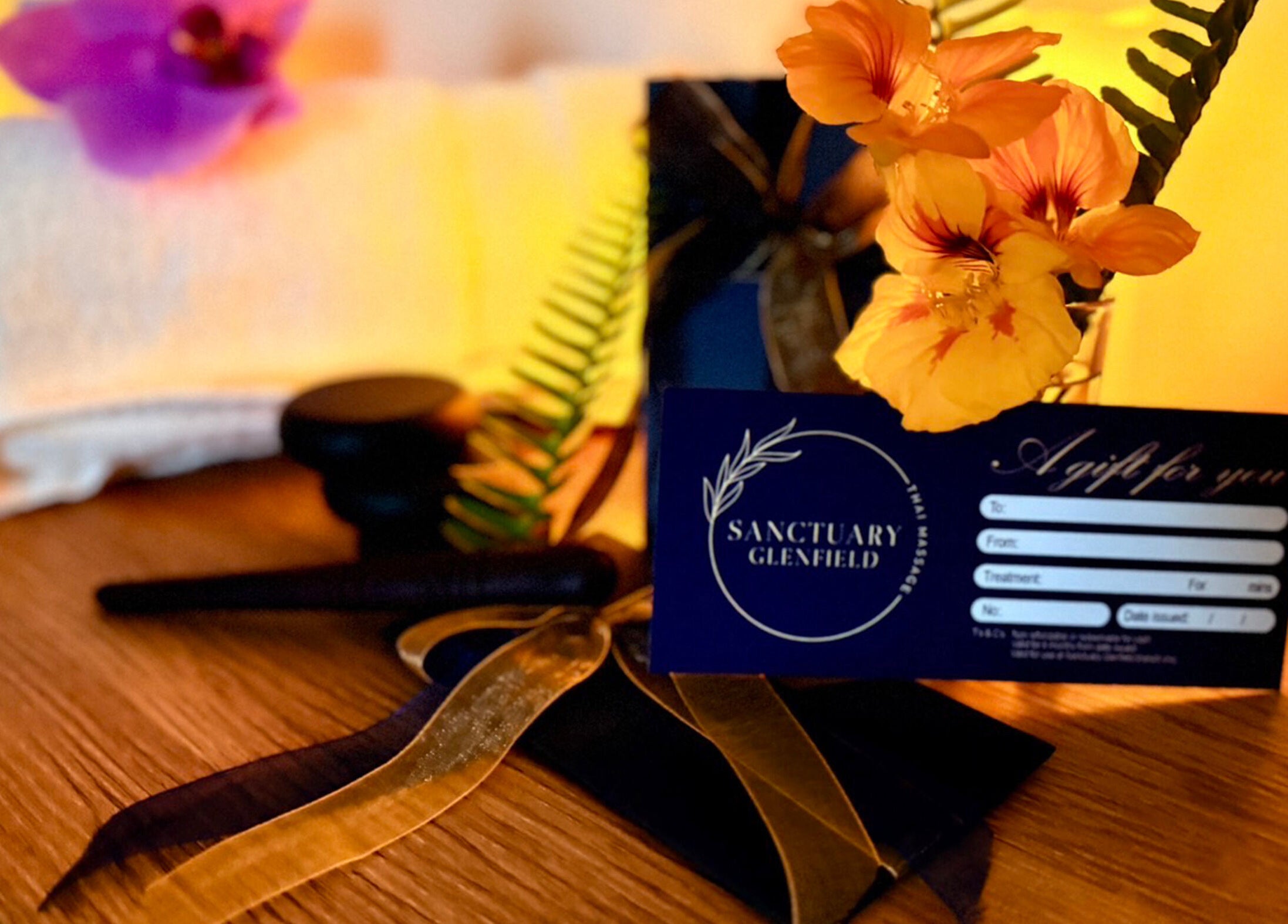 Gift card, flowers, and towel at Sanctuary Glenfield spa in Auckland, NZ offer a luxurious relaxation experience.