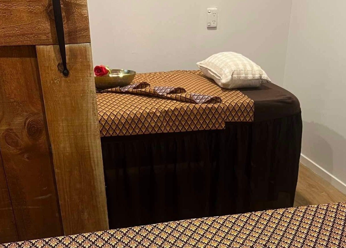 Cozy massage table at Sanctuary Glenfield, Auckland, NZ with ornate linens for a relaxing retreat.