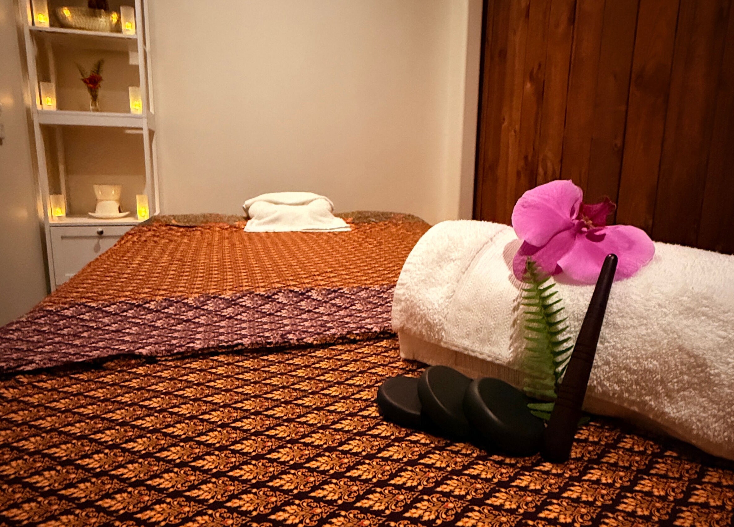Massage room in Sanctuary Glenfield, Auckland, NZ with a serene setup of towels and flowers for relaxation.
