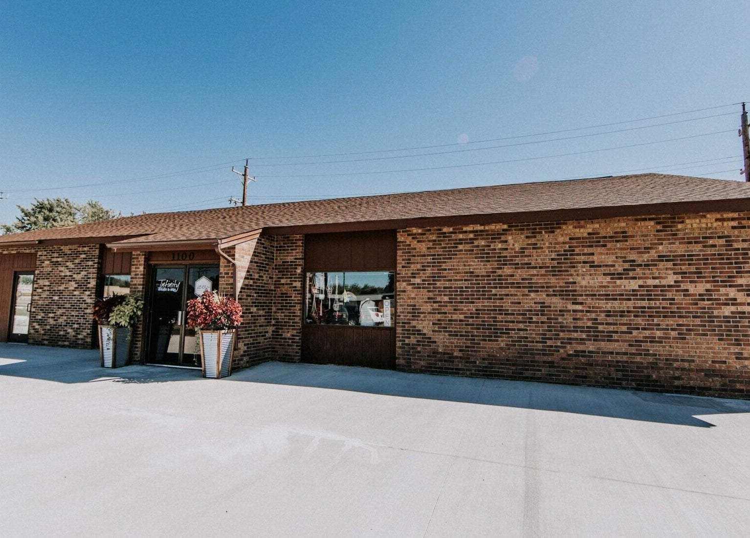 Infinity Salon and Spa's welcoming brick exterior in Mitchell, South Dakota, US under a clear blue sky.