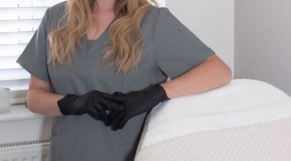 Beauty professional at Radiant Skin By KB in Rhyl, Wales, GB, wearing grey uniform and black gloves.