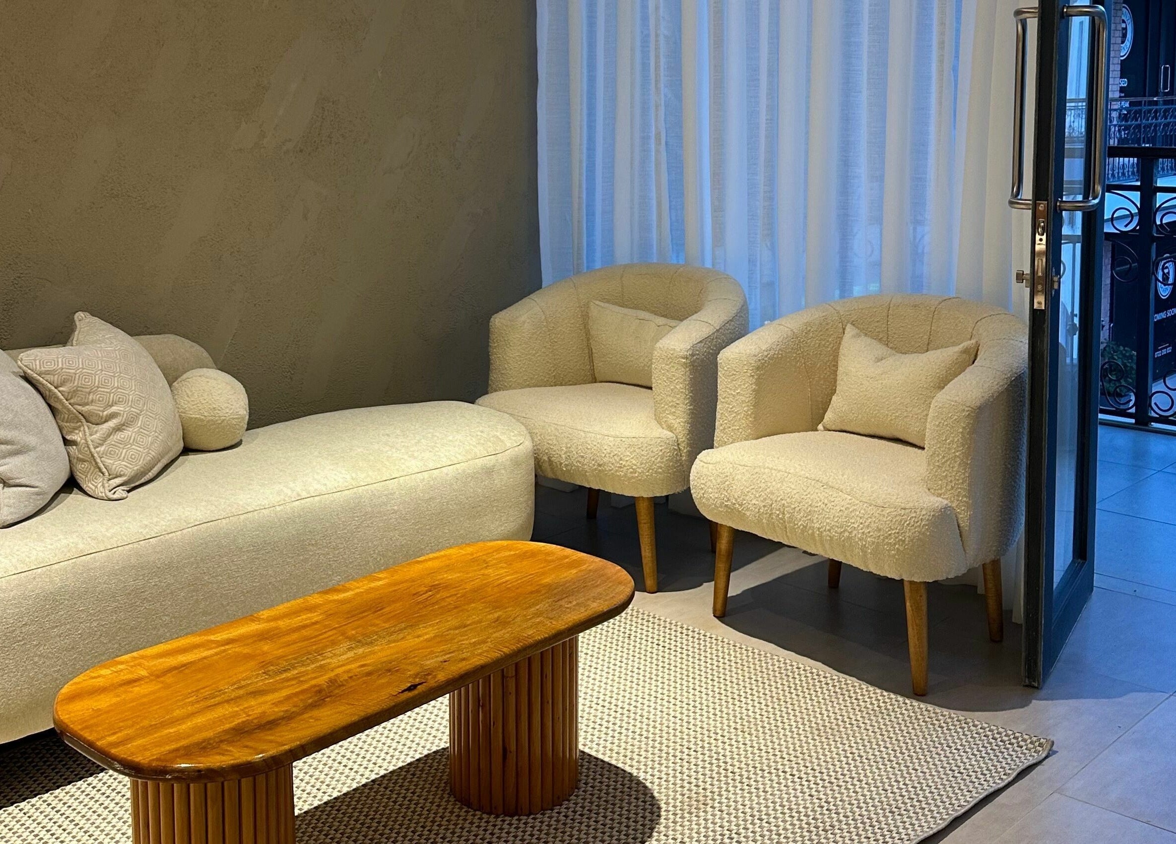 Cozy lounge area at Nuba Spa, Nairobi featuring plush chairs and a wooden table, awaiting guests.