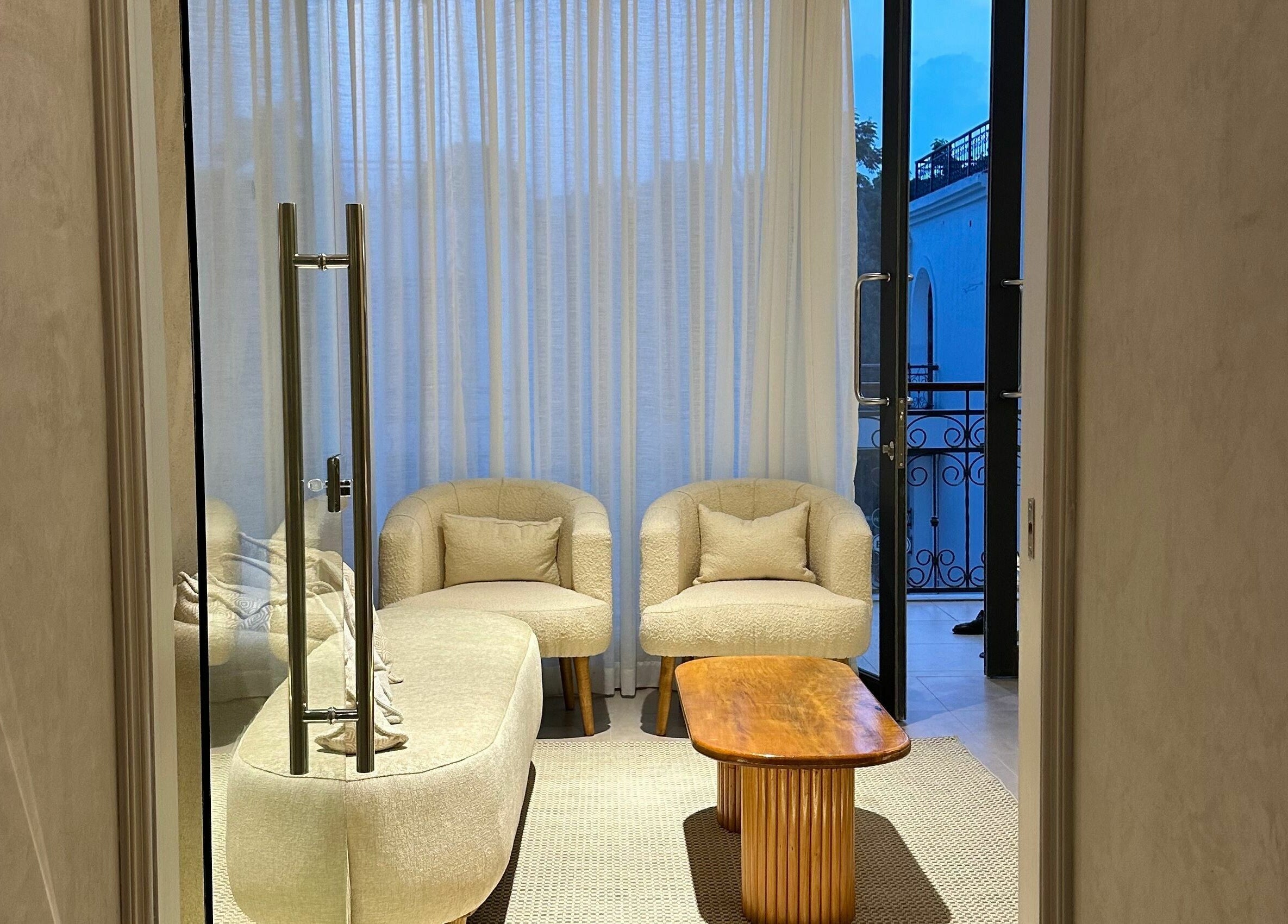 Elegant lounge at Nuba Spa, Nairobi, chairs and table bathed in soft light, offering comfort and tranquility.