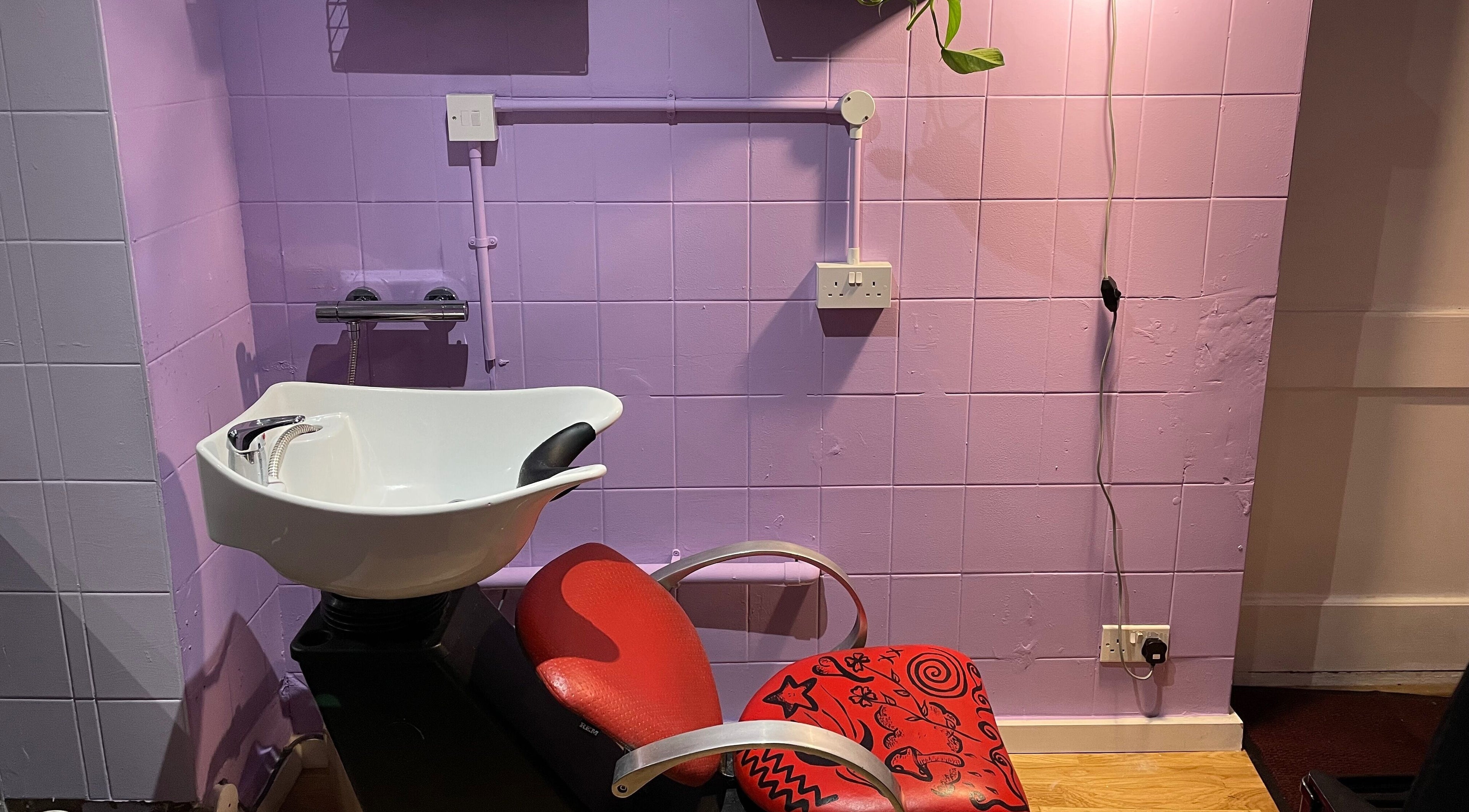 Modern salon chair at Go Coiff Yourself, Brighton And Hove, England, GB. Purple walls enhance the chic vibe.