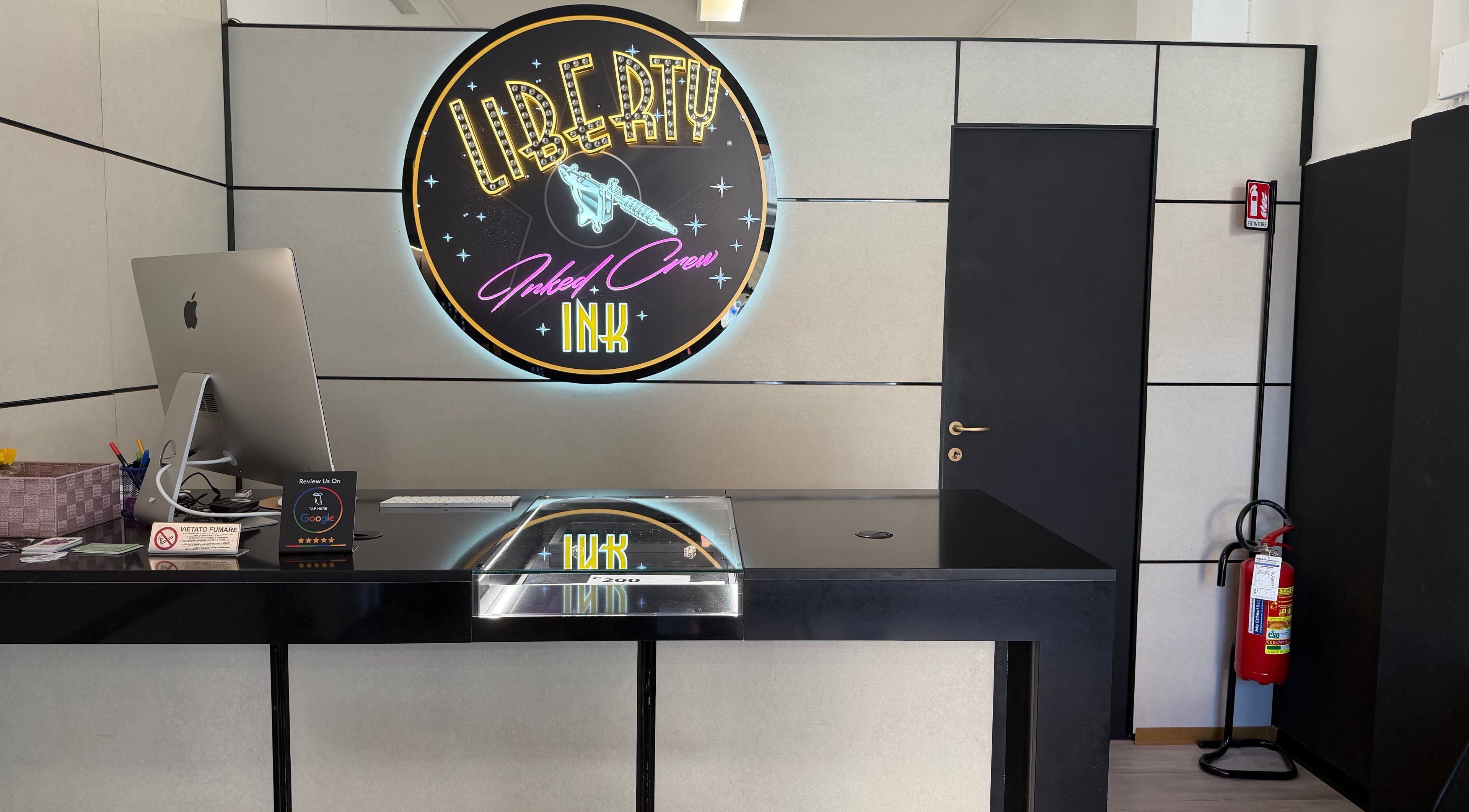 Reception moderna di Liberty Ink Tattoo & Piercing a Firenze, Toscana, IT con logo luminoso.