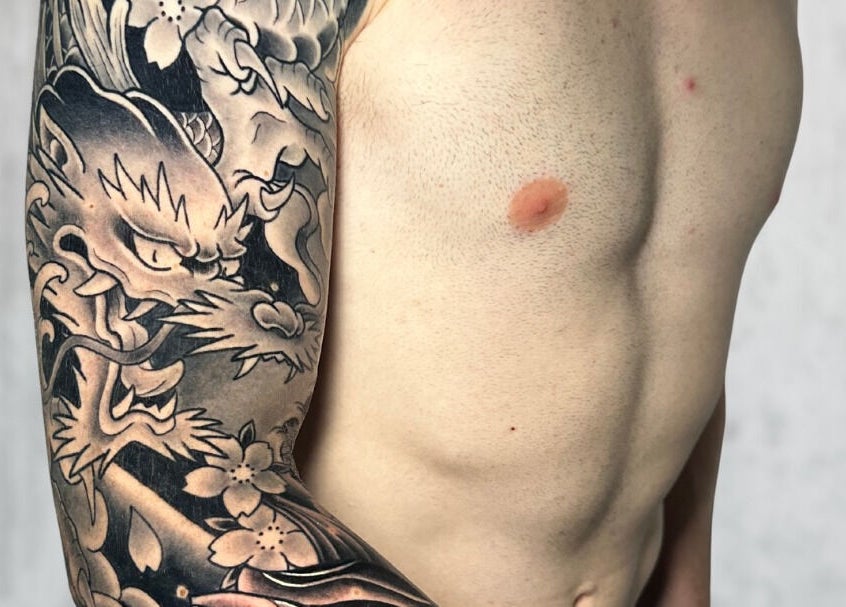 Tatuaggio drago su braccio da Liberty Ink Tattoo & Piercing, Firenze, Toscana, IT. Design dettagliato e intricato.