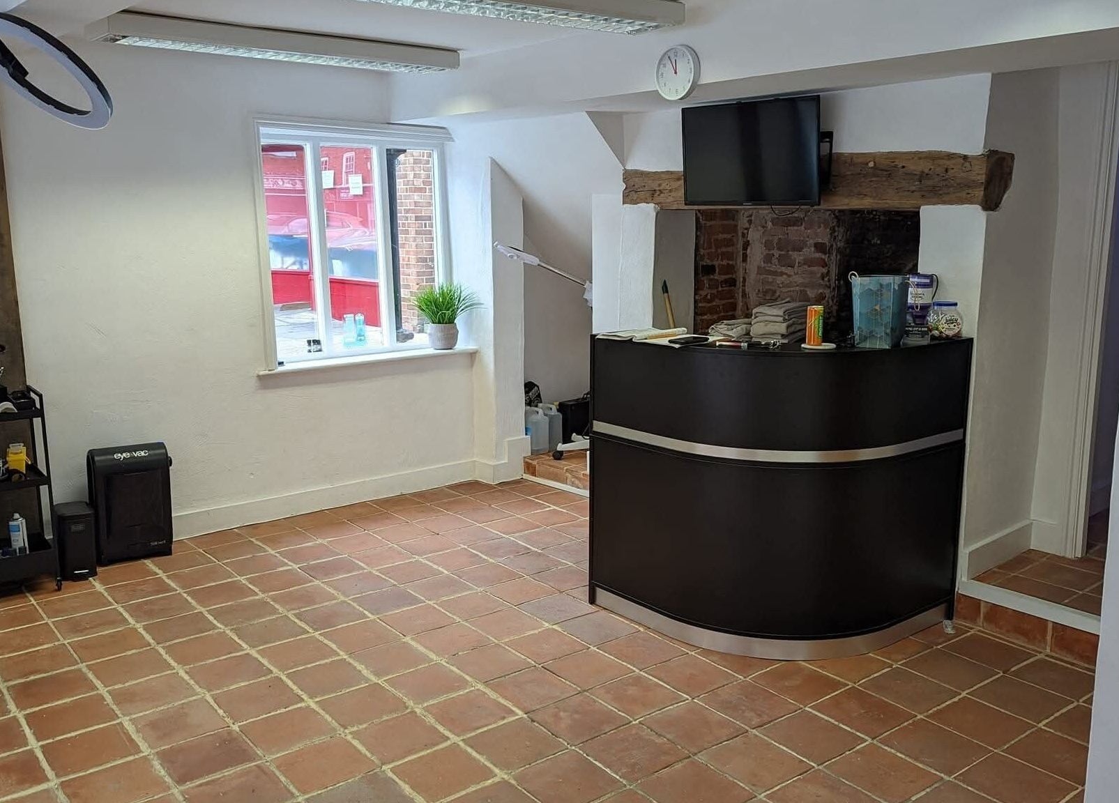 Reception area of chloenortonhair in Dereham, England, GB with a sleek black desk and rustic brick decor.