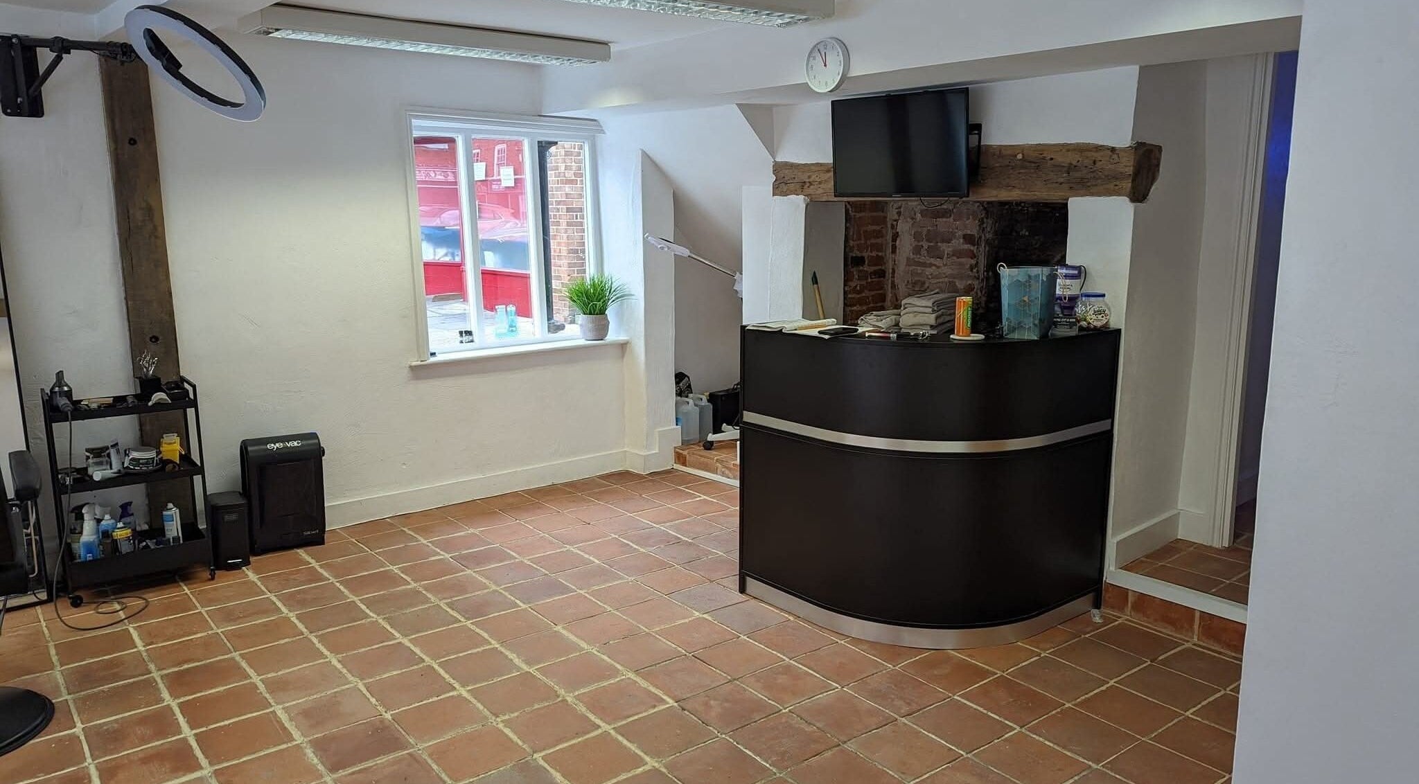 Reception area of chloenortonhair in Dereham, England, GB with a sleek black desk and rustic brick decor.