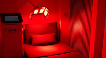 Chic red-lit room at Cryo Revive Manchester, featuring a comfortable bed for wellness treatments. Manchester, England, GB.