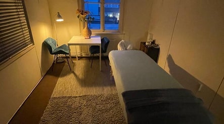Soulage Heals massage room in Amsterdam, Noord-Holland, NL, cozy evening lighting with massage table and chairs.