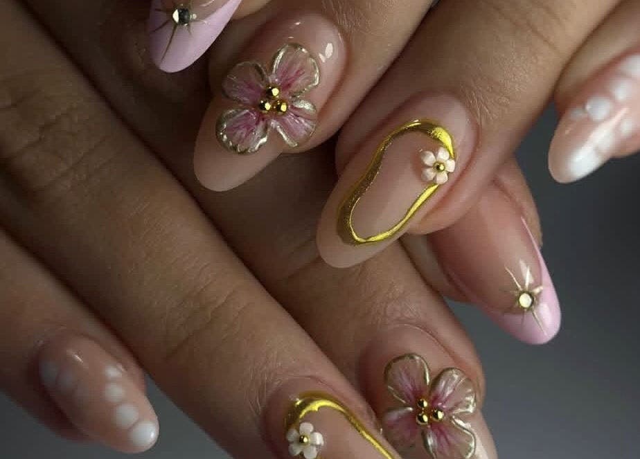 Diseño de uñas florales en Adasat Studio, Canarias, ES, con detalles dorados y flores pintadas.