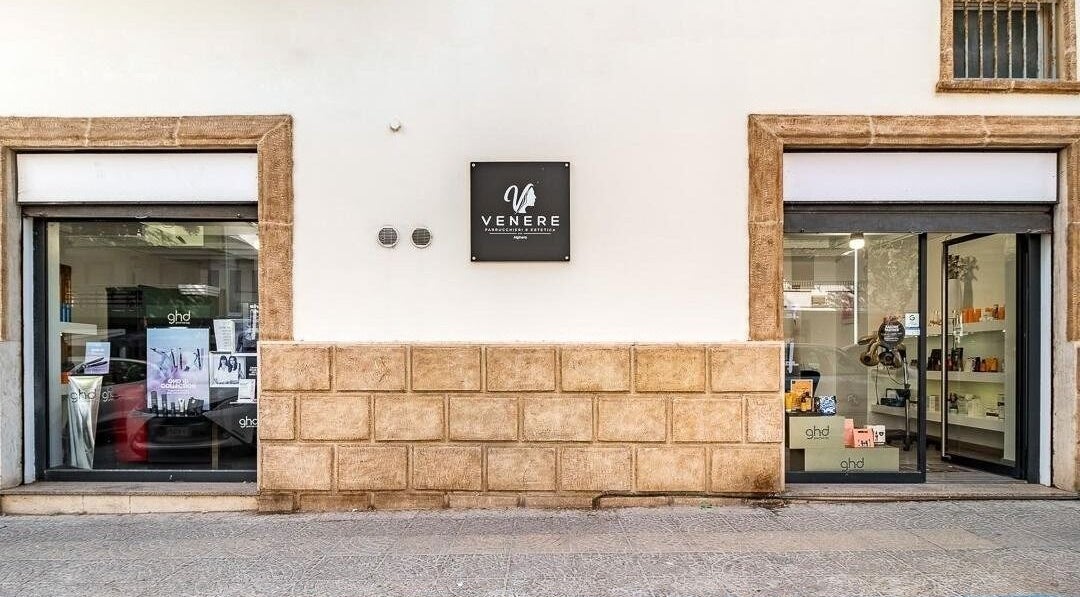 Facciata di Venere Parrucchieri ad Alghero, Sassari, IT, con vetrine moderne e insegna elegante.