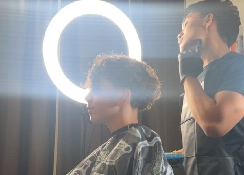 Hair stylist working on a client's hairstyle under ring light at VINCE'S CHOPS, Montréal, Québec, CA.