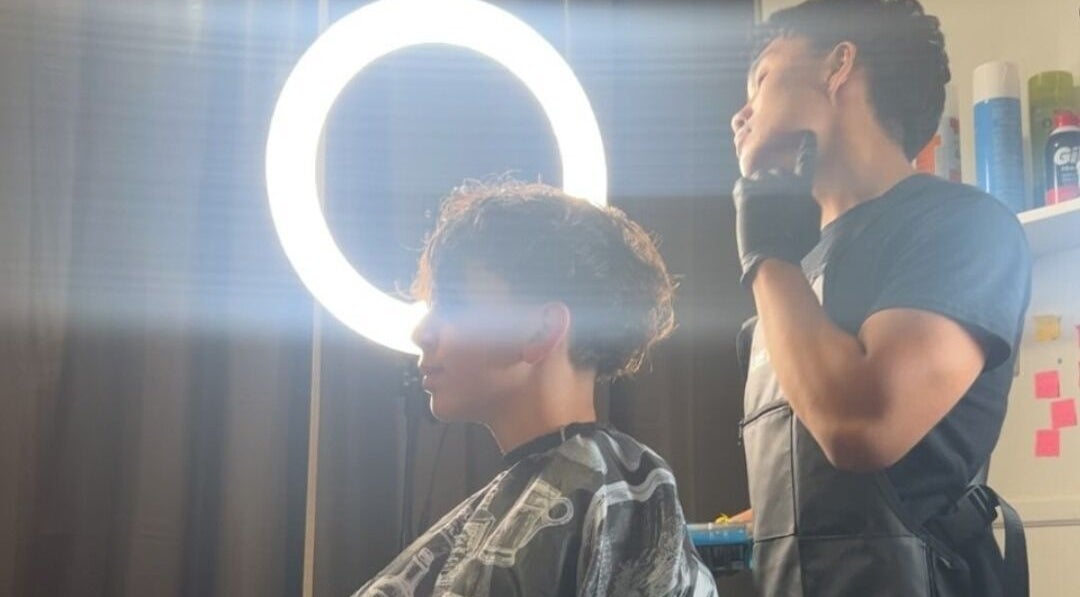 Hair stylist working on a client's hairstyle under ring light at VINCE'S CHOPS, Montréal, Québec, CA.