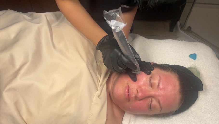 Facial treatment at The Makeup Monk in Costa Mesa, California, US. Aesthetician using a tool on a client's face.