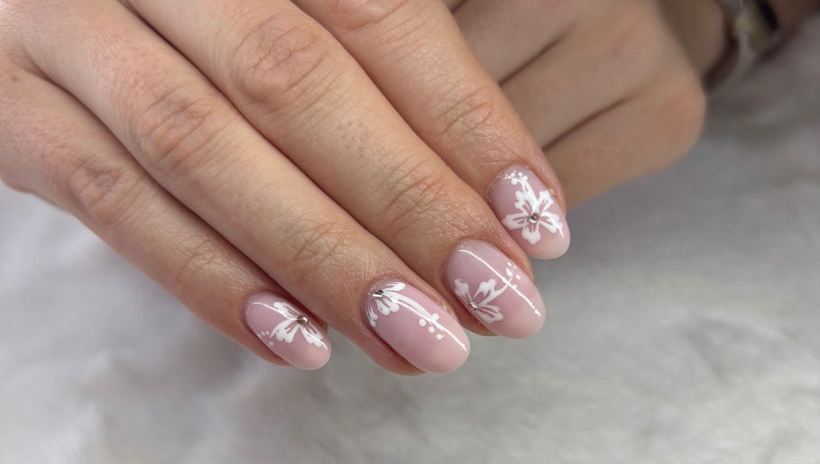 Elegant floral nail art at Vee Oli Nails, Johannesburg, Gauteng, ZA. Delicate white designs on pink nails.