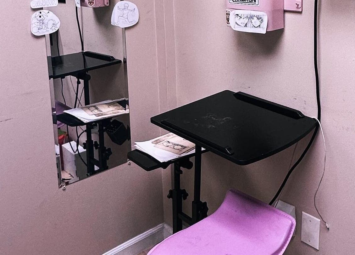 Compact tattoo workspace at K. Tabone Tattoo, Rochester, New York, US, featuring drawings and tools.